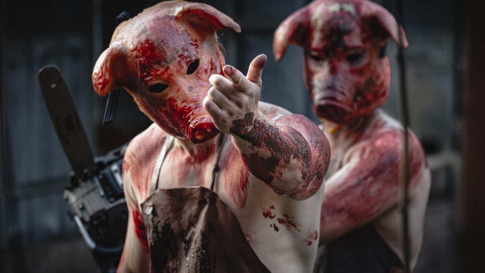 To skuespillere med grisemasker og motorsav i Dystopia Haunted House